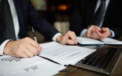 Closeup portrait of unrecognizable successful businessman wearing black formal suit reviewing documents and signing contract during meeting